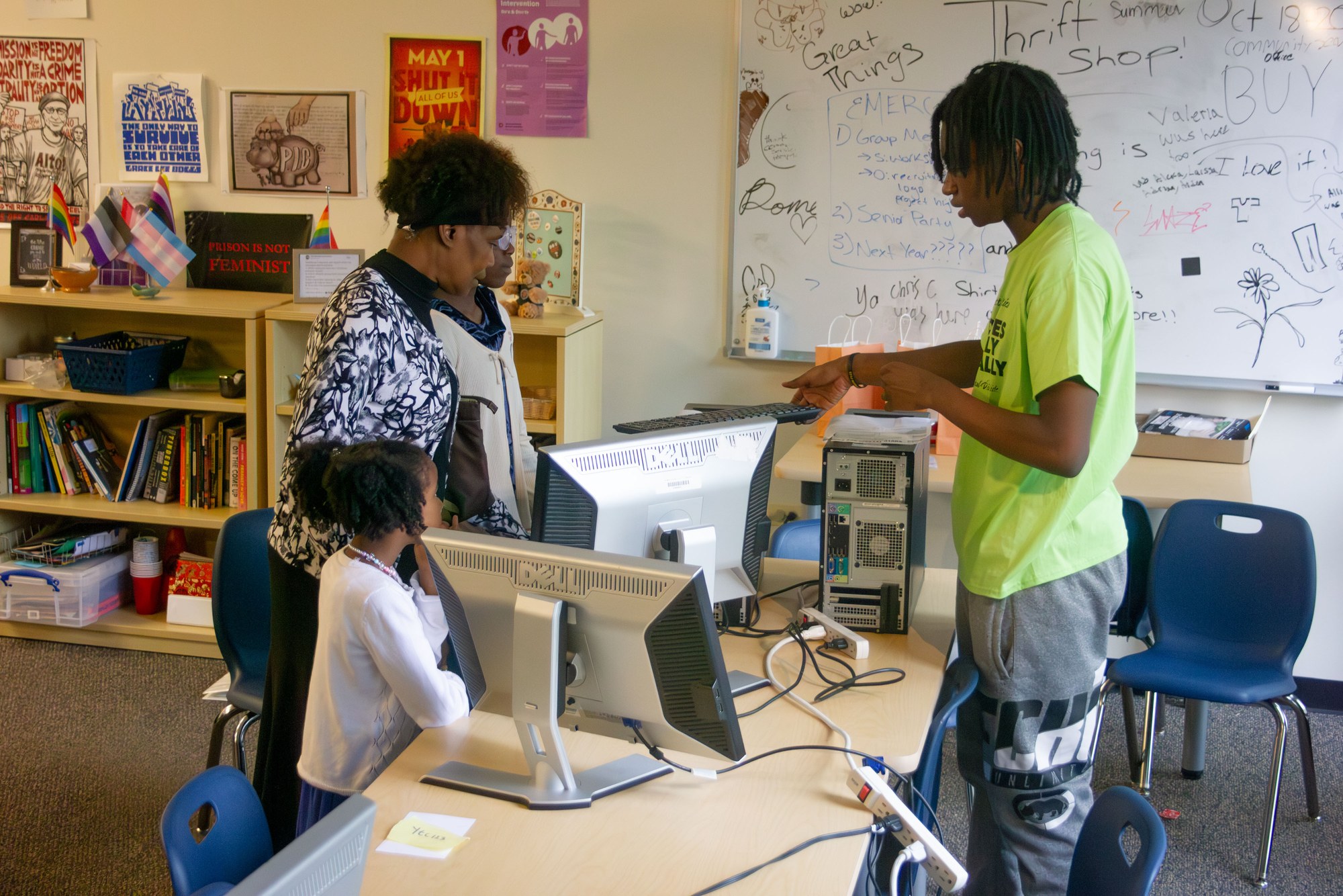 A grandmother and granddaughter are introduced to their new computer by a YTC student in a green YTC shirt