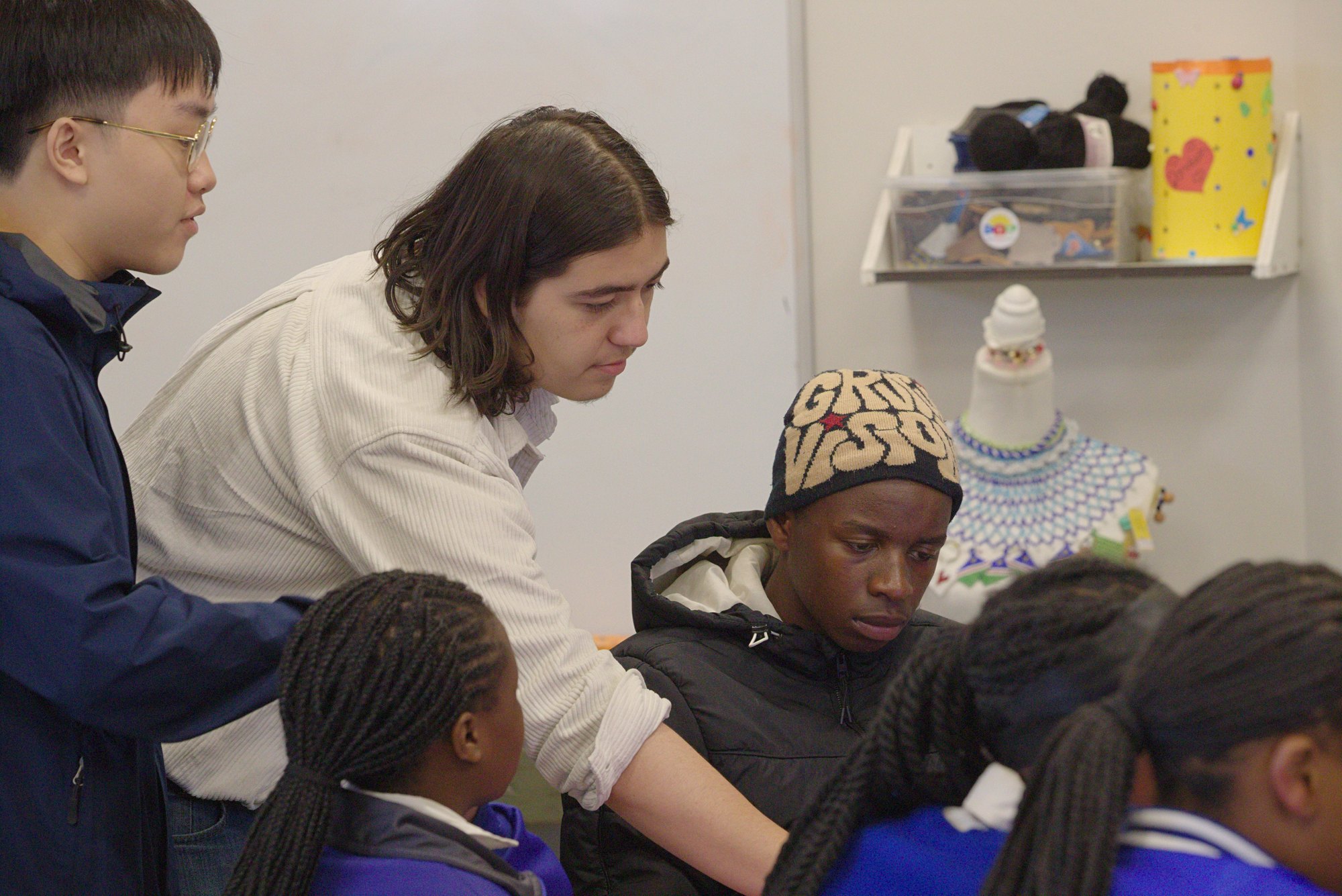 Chris, an ETHS YTC student, leans in to help a Namibian student at his desk